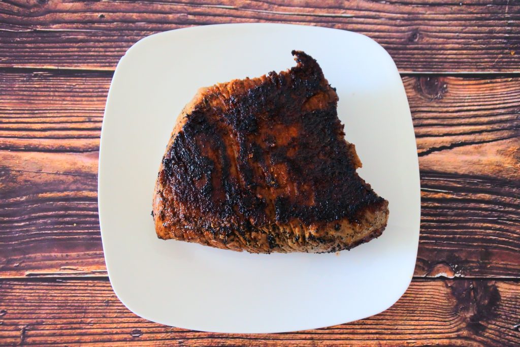 An overhead image of a charred and cooked slab of steak on a plate