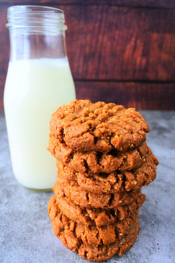 A head on image of a stack of peanut butter cookies with a bottle of milk behind them