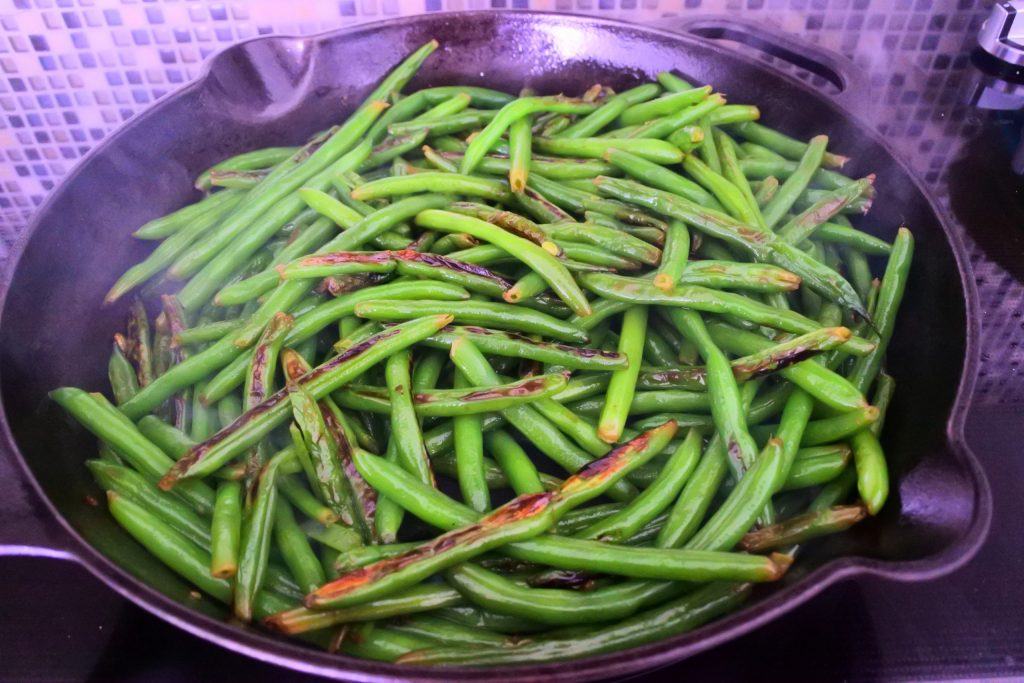 An angled image of a skillet of blistered green beans.