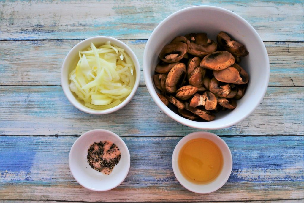 An overhead image of bowls containing sliced onions, mushrooms, oil and salt and pepper