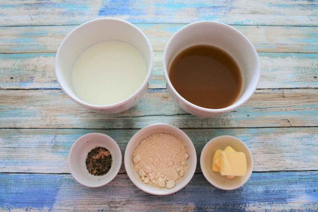 An overhead image of ingredients for a simple roux sauce including milk, broth, butter, whole wheat pastry flour and salt and pepper