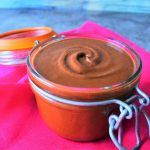 A head on image of homemade chocolate hazelnut spread in a jar on a pink linen napkin