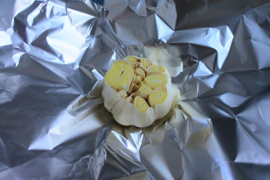 An overhead image of a cut head of garlic on a sheet of foil paper