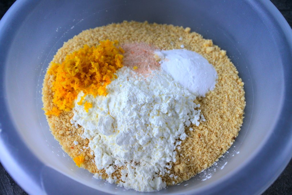 A close up image of a bowl of almond flour with baking soda, salt, lemon zest and potato starch added on top