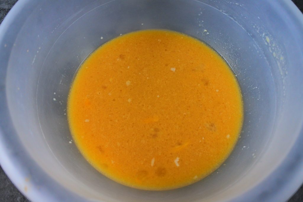 An overhead image of a bowl of wet ingredients mixed together to give a yellow color.