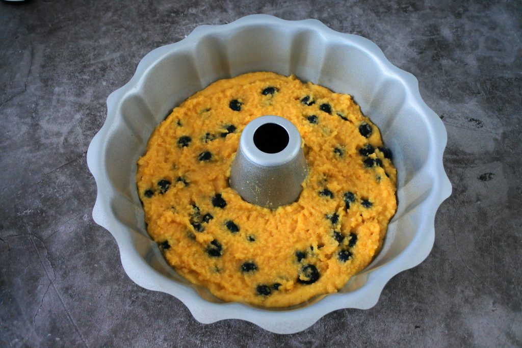 An over head image of the lemon and blueberry batter being poured into the greased bundt pan