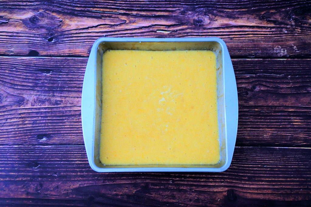 An overhead image of a square cake pan filled with lemon cake batter