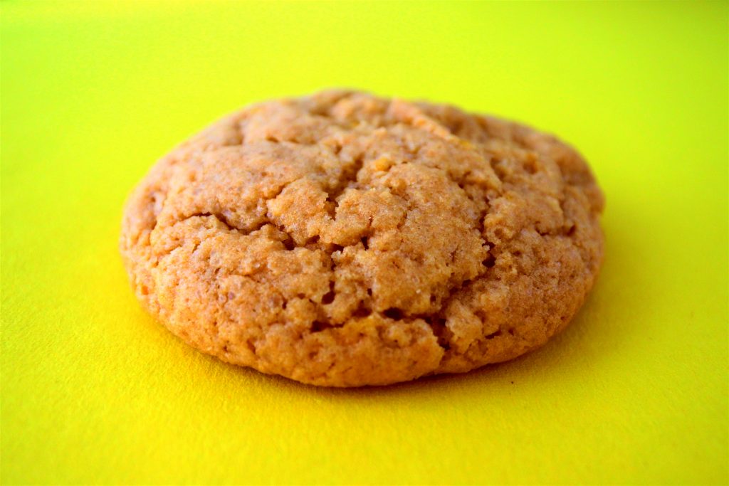 Close up image of a lemon sugar cookie with a cracked top on a yellow background
