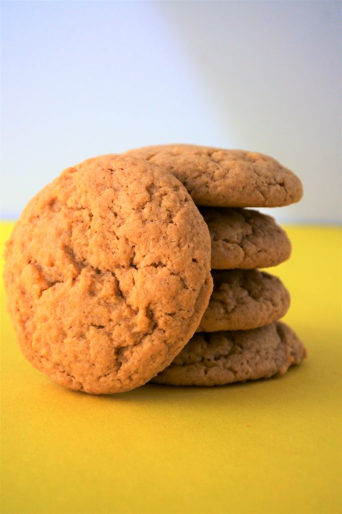 A head on, close up image of a stack of lemon sugar cookies with one cookie leaned against the stack