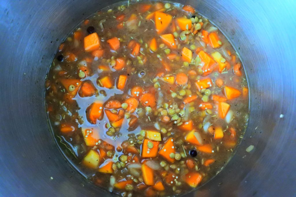 An overhead image of quinoa and lentils with vegetables simmering in a pot