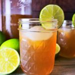 Head on image of jars of limeade served with ice surrounded by fresh limes