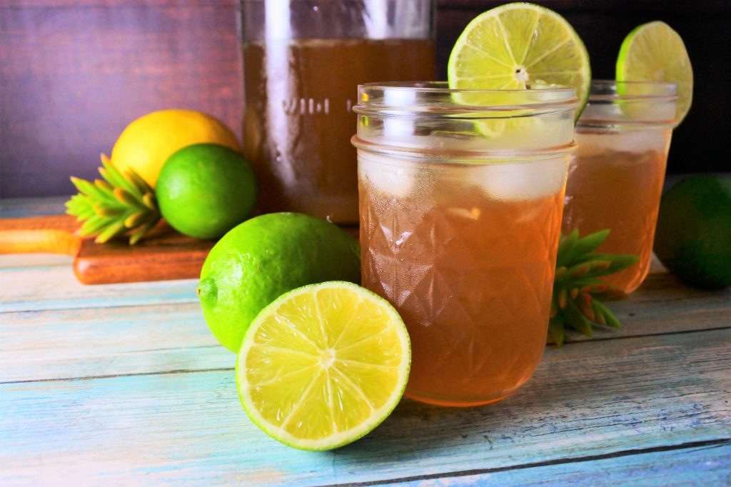Head on image of jars of limeade served with ice surrounded by fresh limes