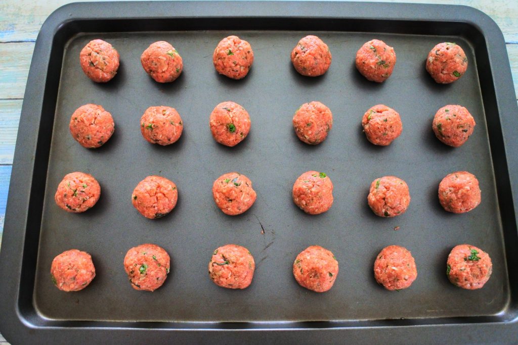 An overhead image of a tray of uncooked meatballs