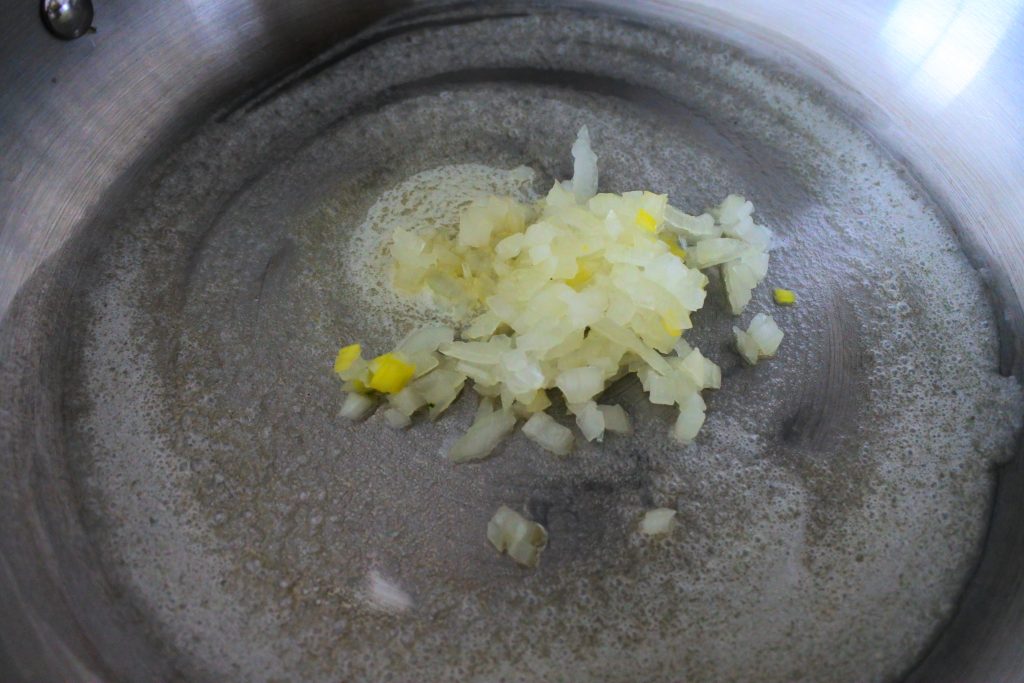 A close up image of a sautepan with melted butter and chopped onions