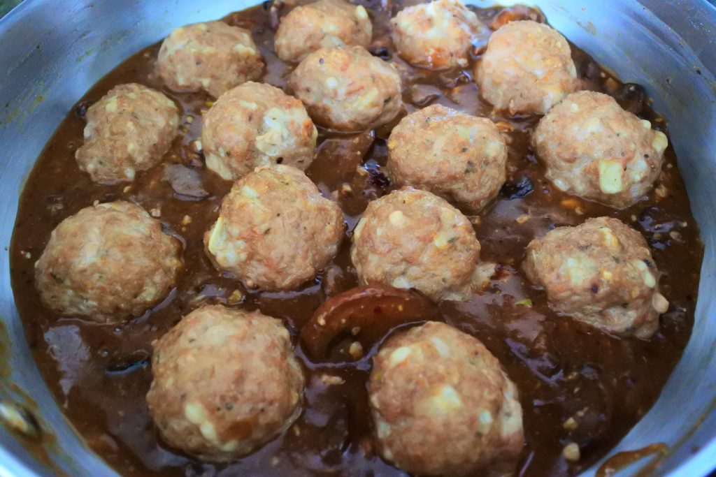A close up image of a saute-pan with gravy and baked turkey meatballs.