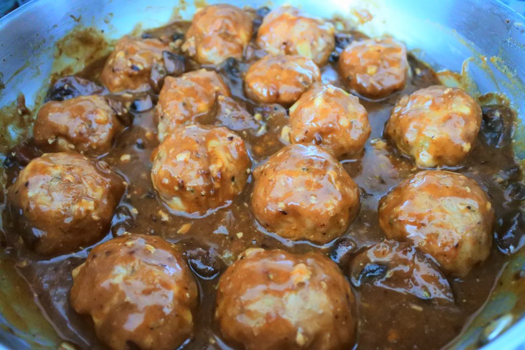 A close up image of a saute-pan of turkey meatballs smothered in a mushrooms and onion gravy
