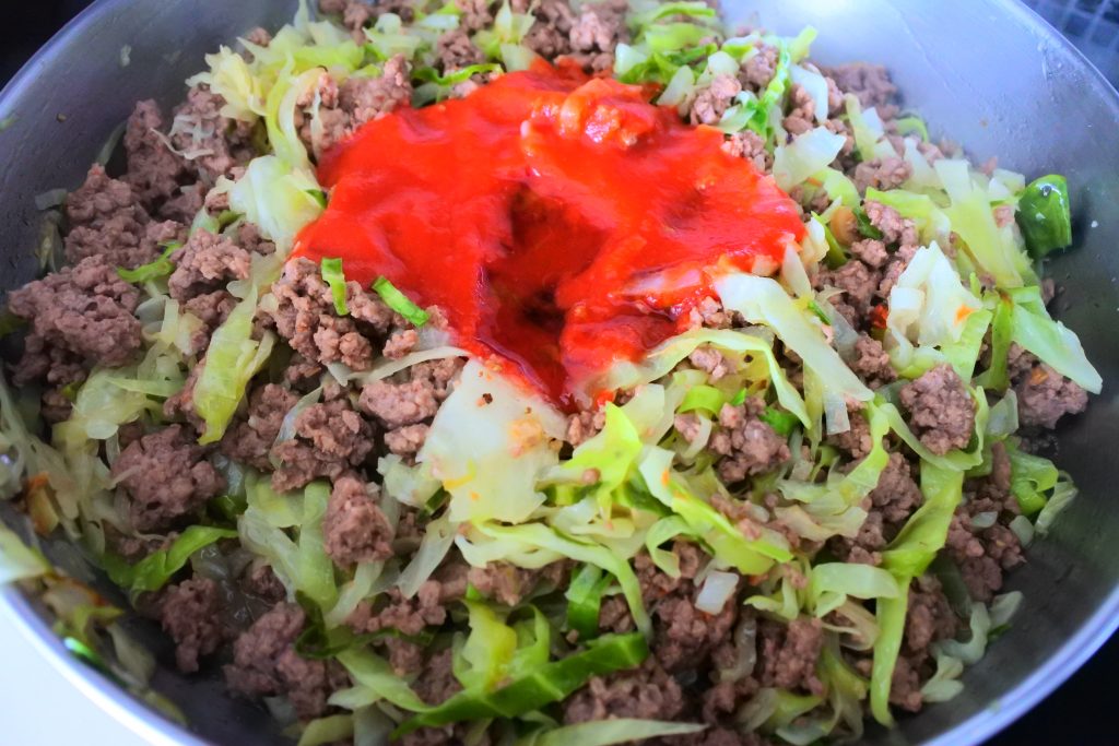 A close up image of a skillet of ground beef and cabbage with tomato sauce and honey