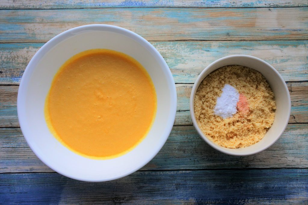 An overhead image of a bowl containing a mixture of wet ingredients and another of a mix of dry ingredients for a chocolate chip muffin batter.