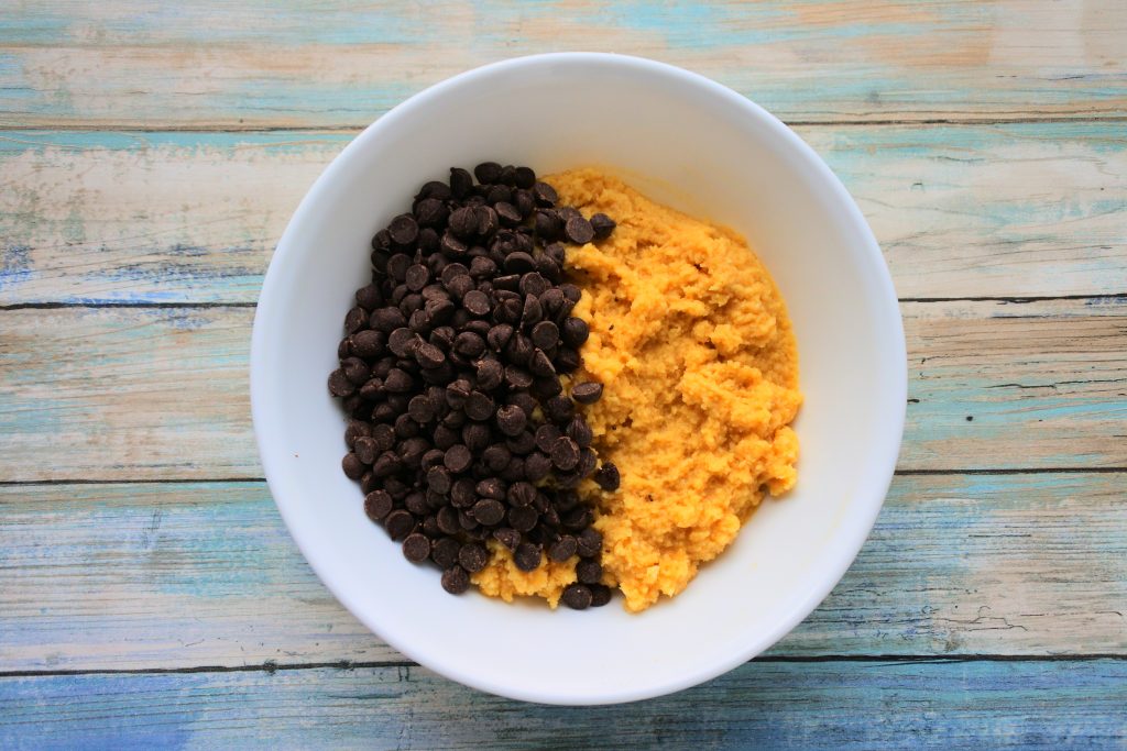 An overhead image of a bowl of muffin batter with chocolate chips on top