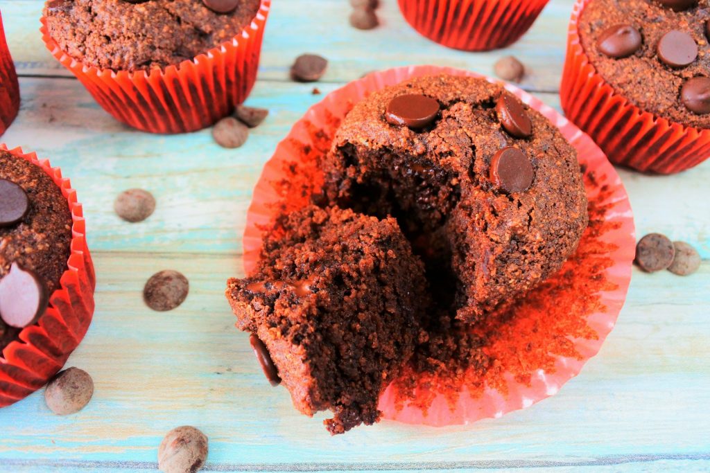 An overhead close up on a gluten free double chocolate muffin with the paper liner peeled off and the muffin cut open