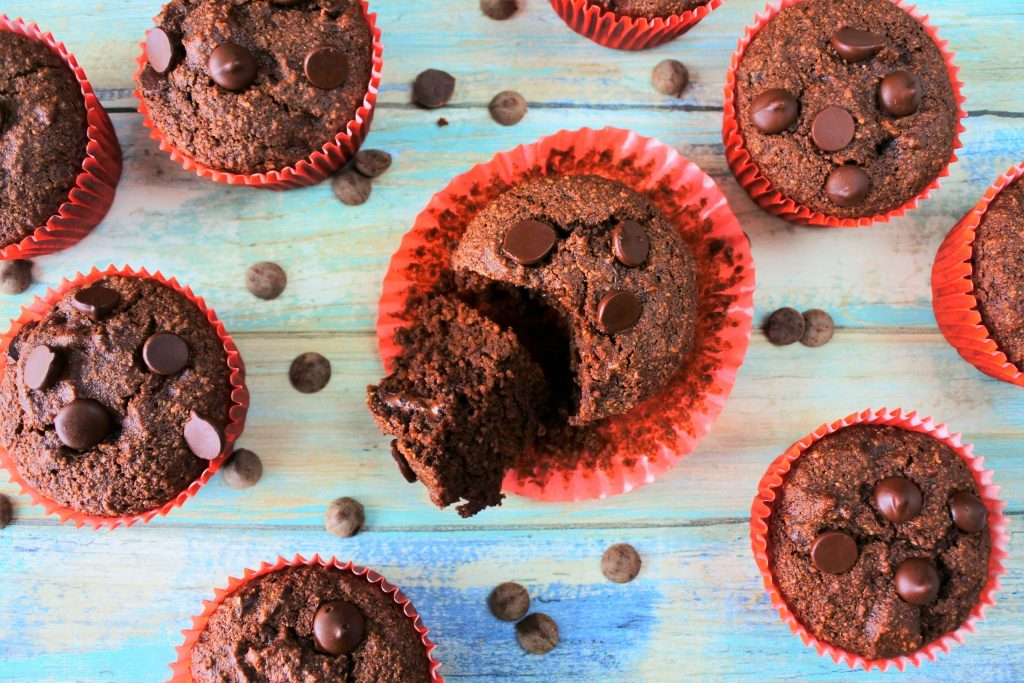 An overhead image of a gluten free double chocolate muffin with the paper liner peeled off and the muffin cut open