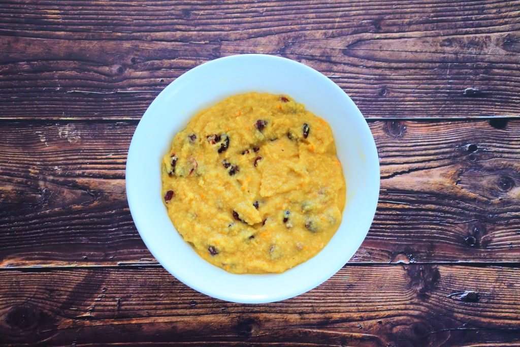 An overhead image of a bowl containing orange cranberry muffin batter