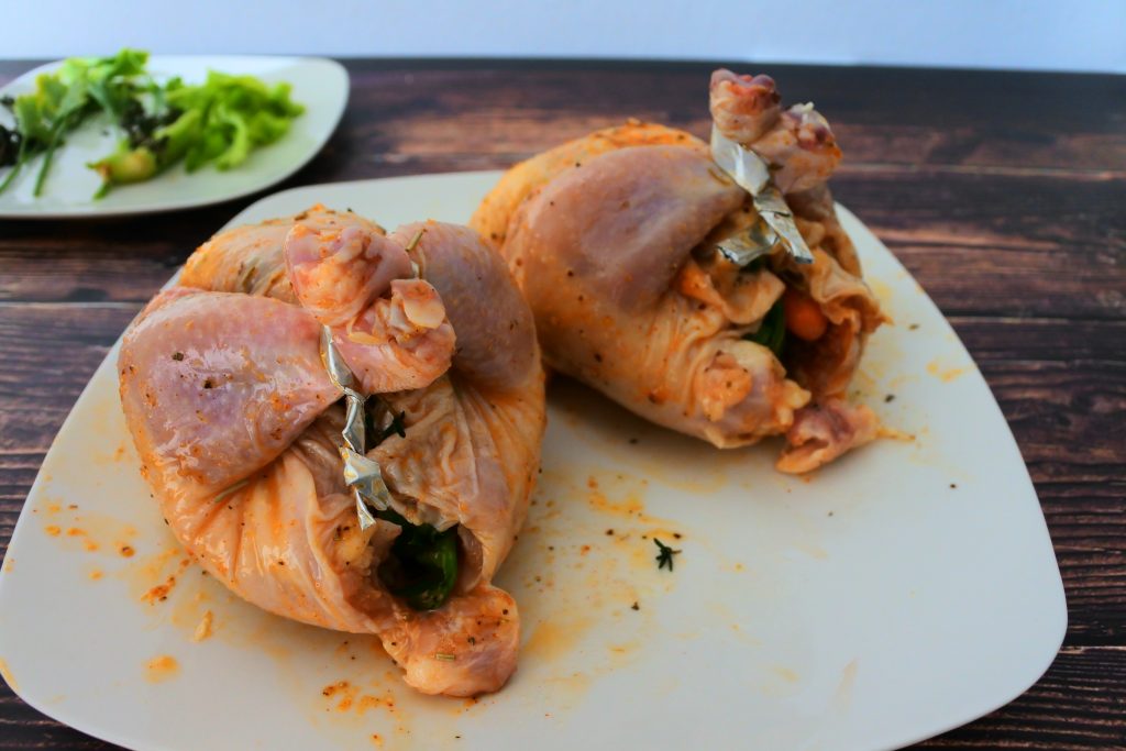 A close up image of two prepped cornish game hens on a plate
