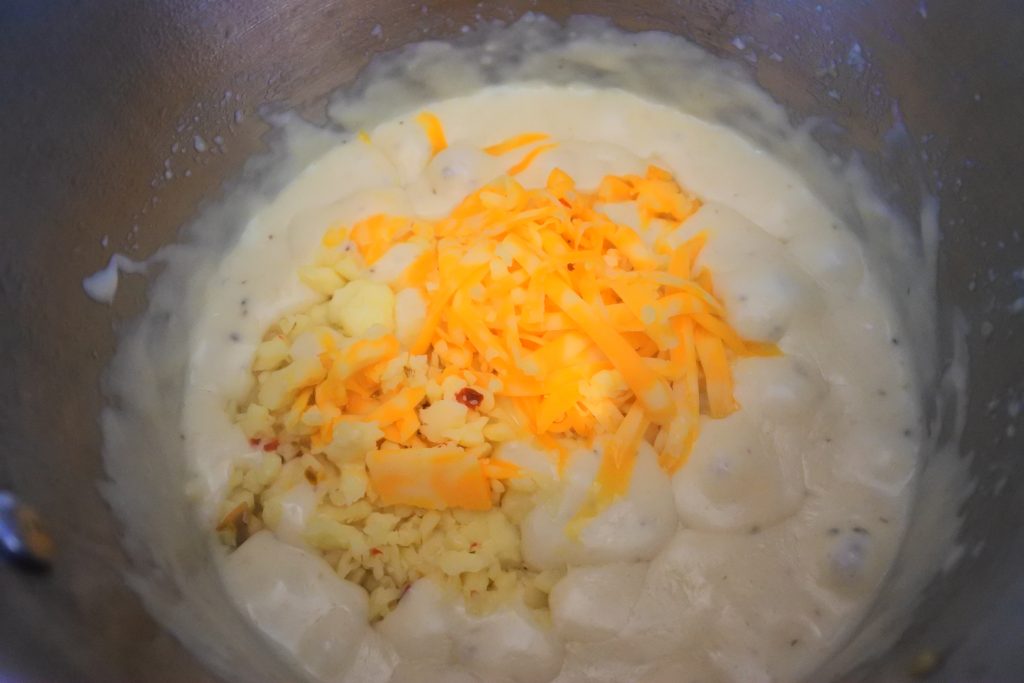 An overhead image of a roux sauce with shredded cheese added in