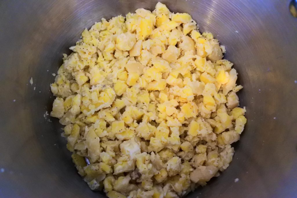 An overhead image of diced green bananas in a pot