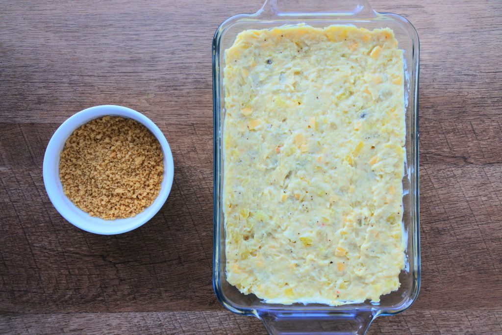 An overhead image of a green banana pie with a dish of whole wheat breadcrumbs to the side