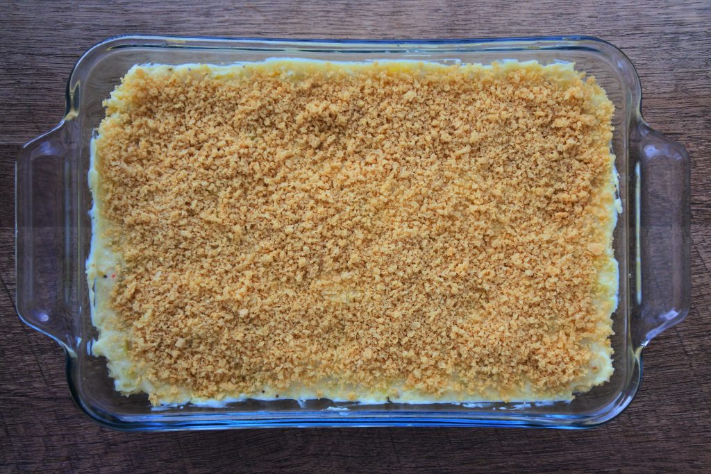 An overhead image of a green banana pie with an unbaked breadcrumb top