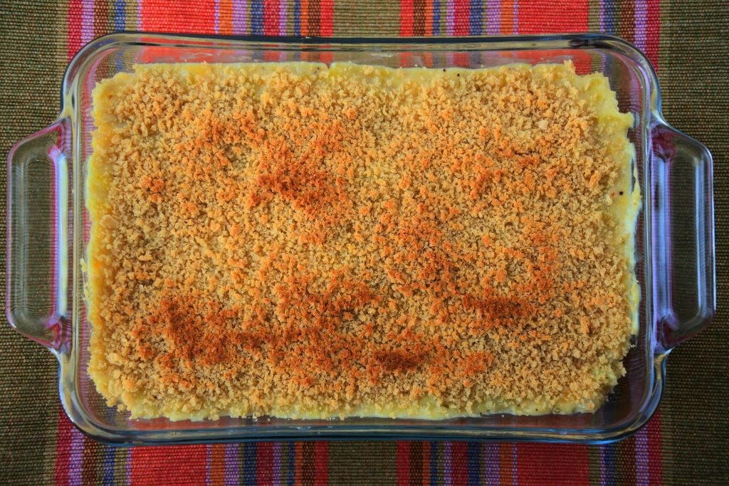 An overhead image of a green banana pie with a baked and browned top