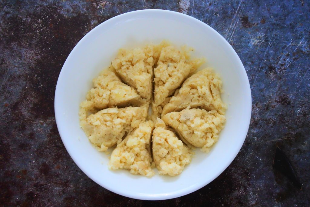 An overhead image of a bowl of mashed and seasoned potato sectioned into equal portions