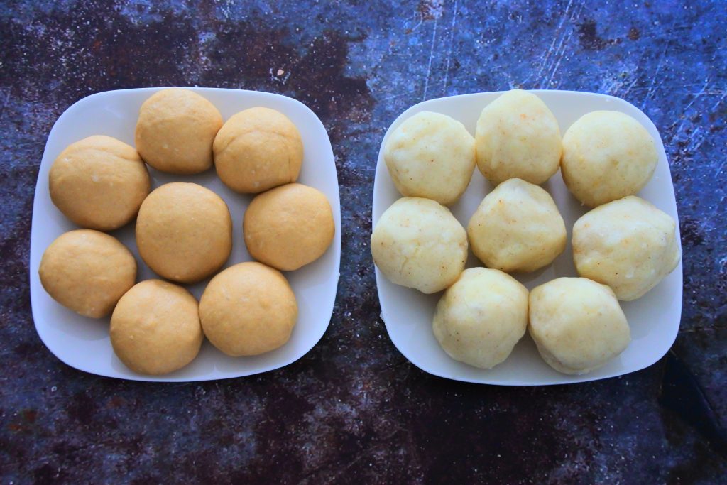 An overhead image of two plates one containing dough balls for potato samosas and the other containing seasoned mashed potato divided and rolled into equal balls.