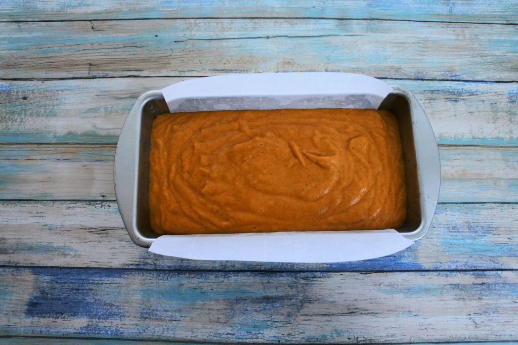 An overhead image of batter for pumpkin spiced bread in a greased and parchment lined pan