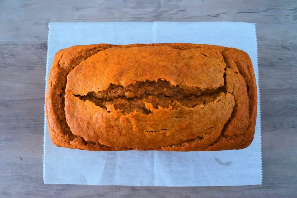 An overhead image of a freshly baked loaf of pumpkin spice bread on a piece of parchment paper