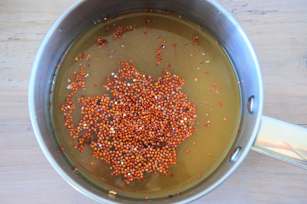 An overhead image of a pot with broth and uncooked quinoa