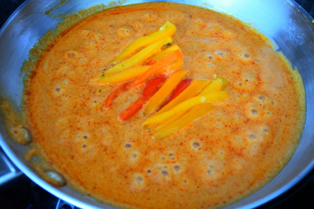 An overhead image of a pan of red thai curry with peppers