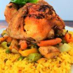 An image of a cornish game hen on a bed of vegetables and some coconut saffron rice