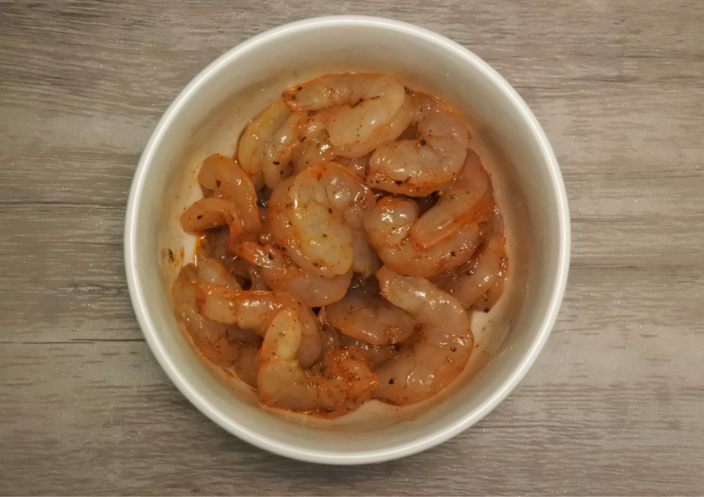 An overhead image of a bowl of uncooked chipotle-seasoned shrimp