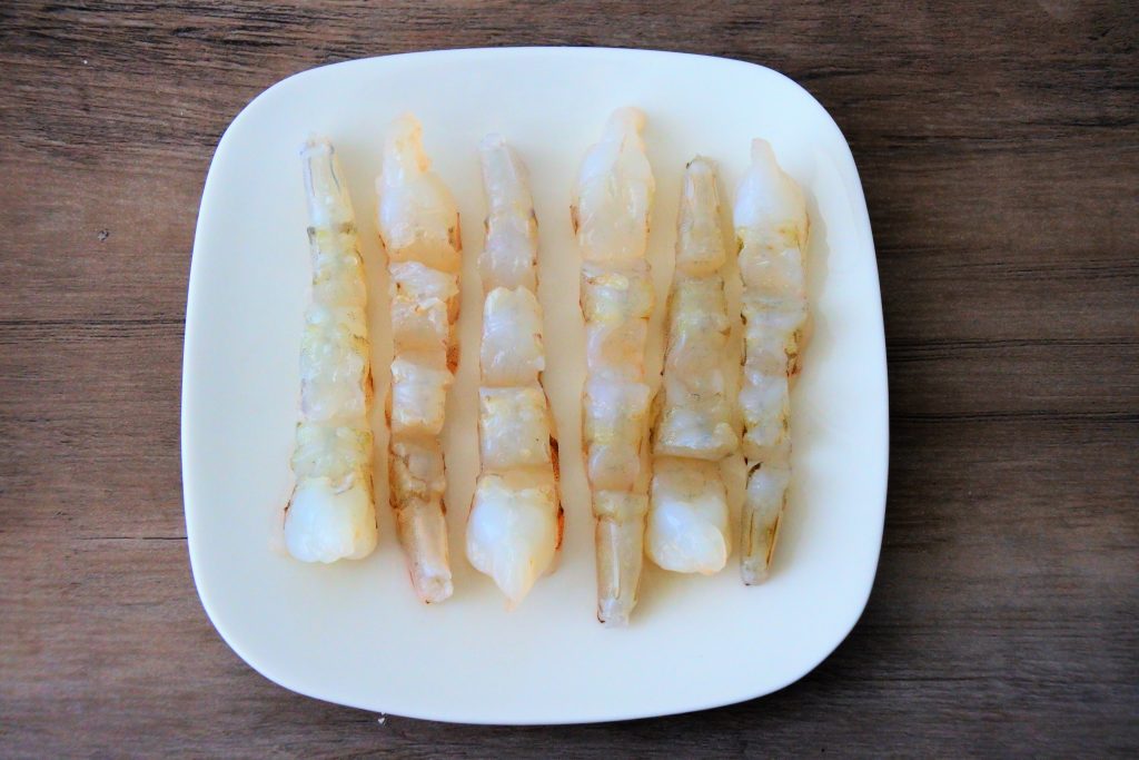 An overhead image of shrimp that's been notched and laid out straight