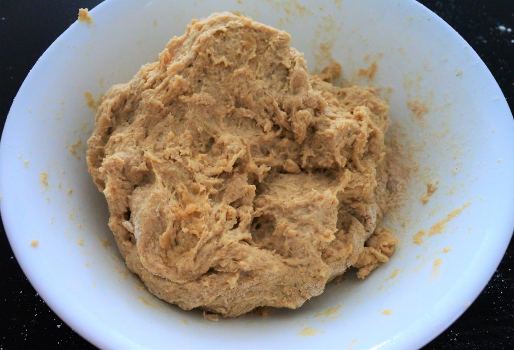 A close up image of a sticky whole wheat dough in a white bowl