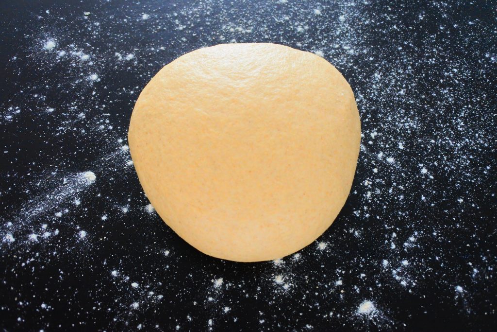 A close of image of a large dough ball on a floured surface