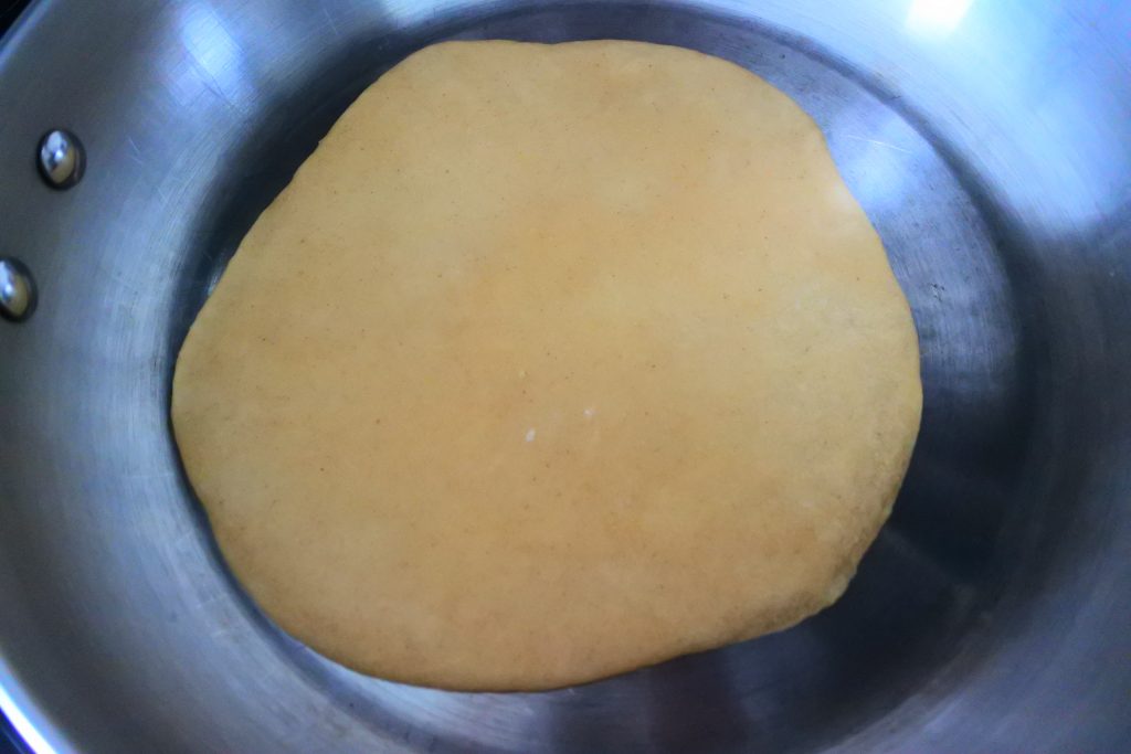 An overhead image of a whole wheat tortilla cooking in a skillet
