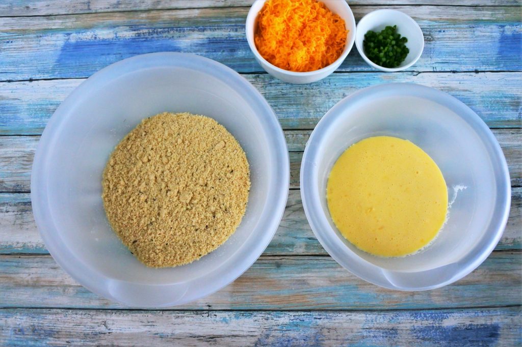 An overhead image of bowls containing wet and dry ingredients for a sour cream and chive cheddar biscuit dough as well as a bowl of finely shredded cheddar and a small dish of chives