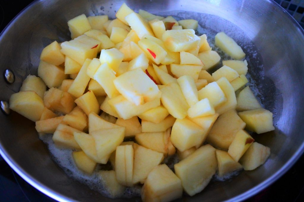 An overhead angled image of apple chunks in a skillet with melted butter