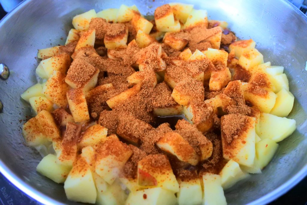 An overhead angled image of apple chunks in a skillet with coconut sugar added on top