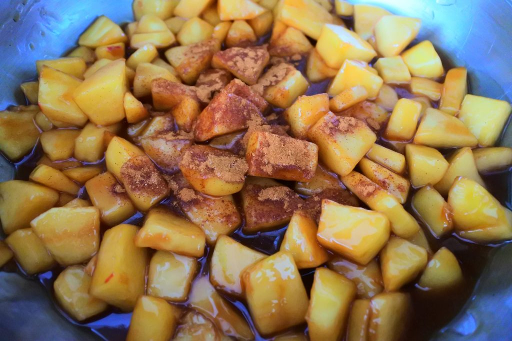 An overhead angled image of apple chunks in a skillet with spices on top