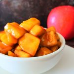 A head on image of a white bowl of Southern Fried Apple chunks with a whole apple in the background