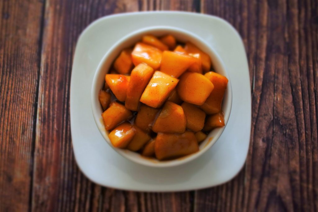 An overhead image of southern fried apples in a white bowl on a wooden surface